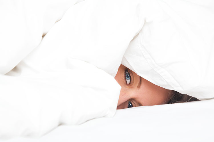 Woman-sleeping-with-head-under-comforter-and-bed-sheets